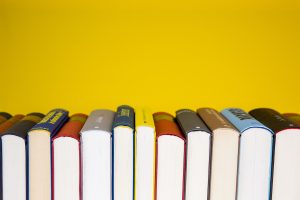 The image has a yellow background and shows a row of books