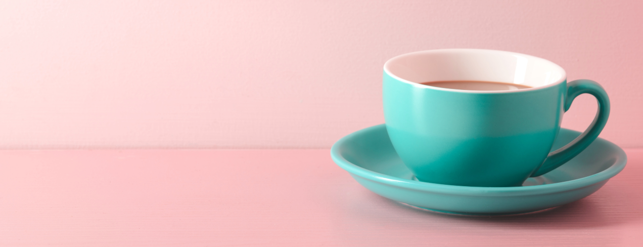 a turquoise coffee cup sits on a pale pink background