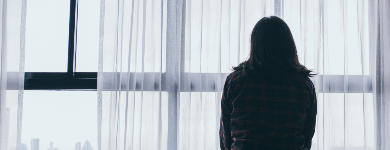 A person faces a window, in silhouette