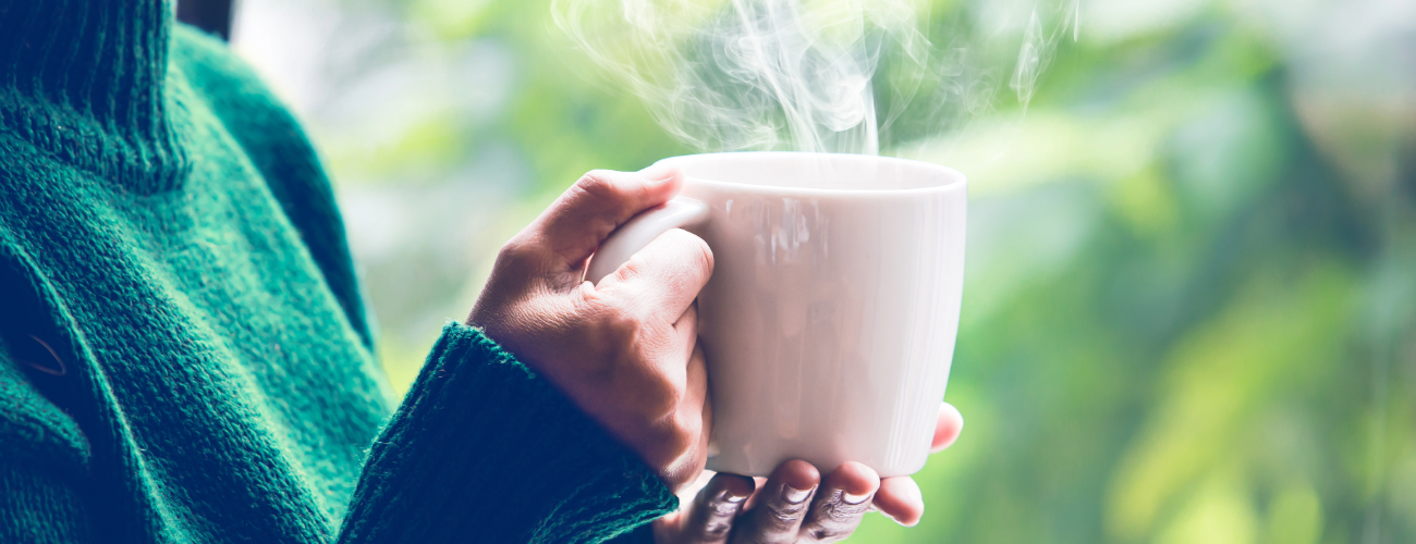 Two hands hold a mug of steaming hot tea