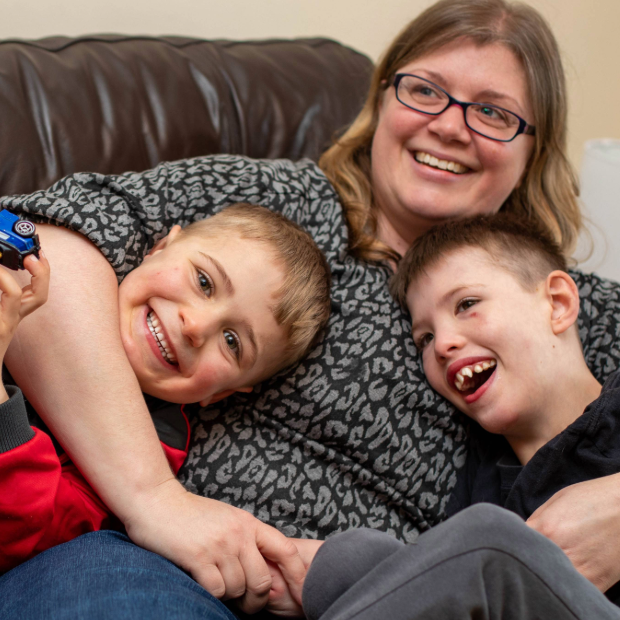 A mum and her two boys hug on the sofa